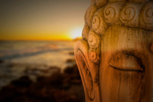 Buddha figure meditating with a sunrise on the beach, Spain